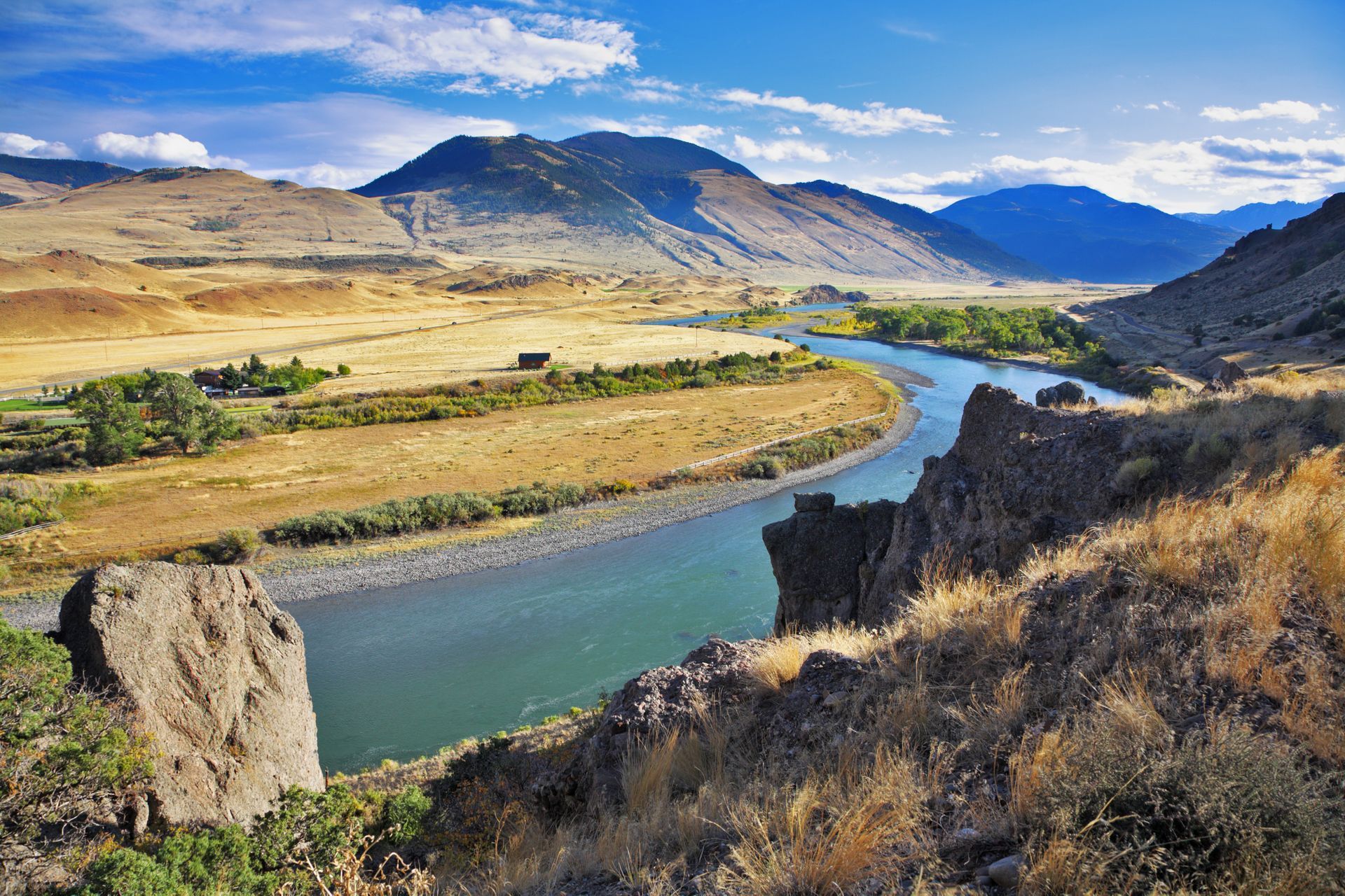 A river flowing through a valley with mountains in the background