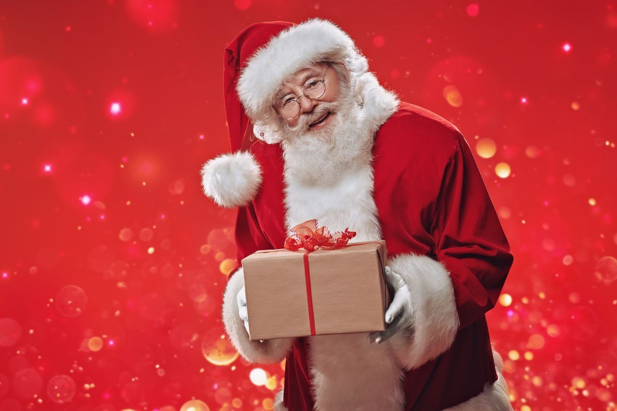 Santa claus is holding a gift box on a red background.