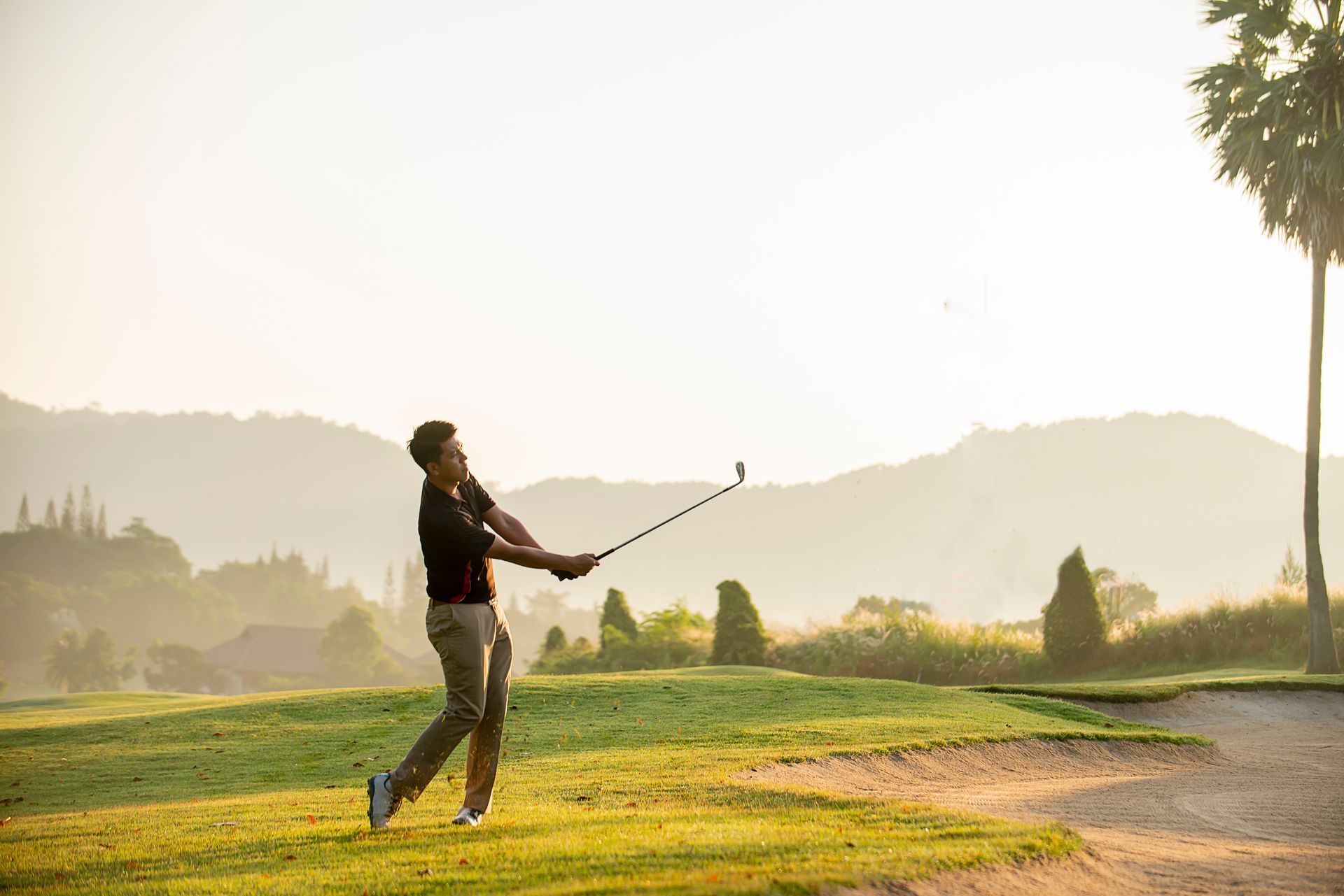 A man is swinging a golf club on a golf course.