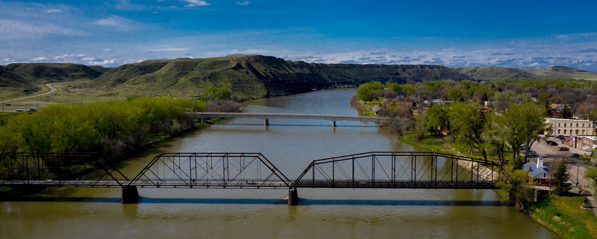 An aerial view of a bridge over a river surrounded by trees.