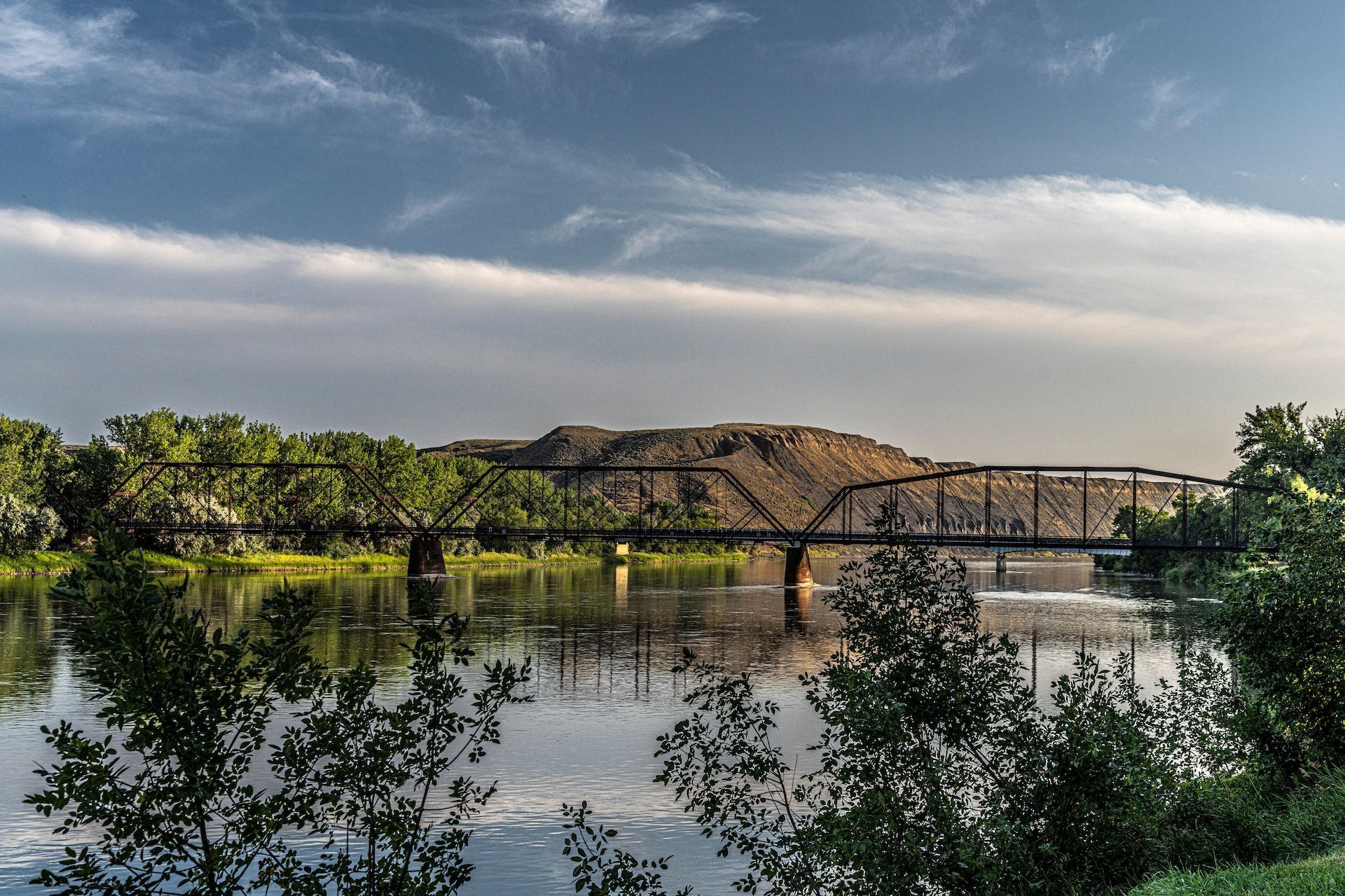 A bridge over a river with a mountain in the background.