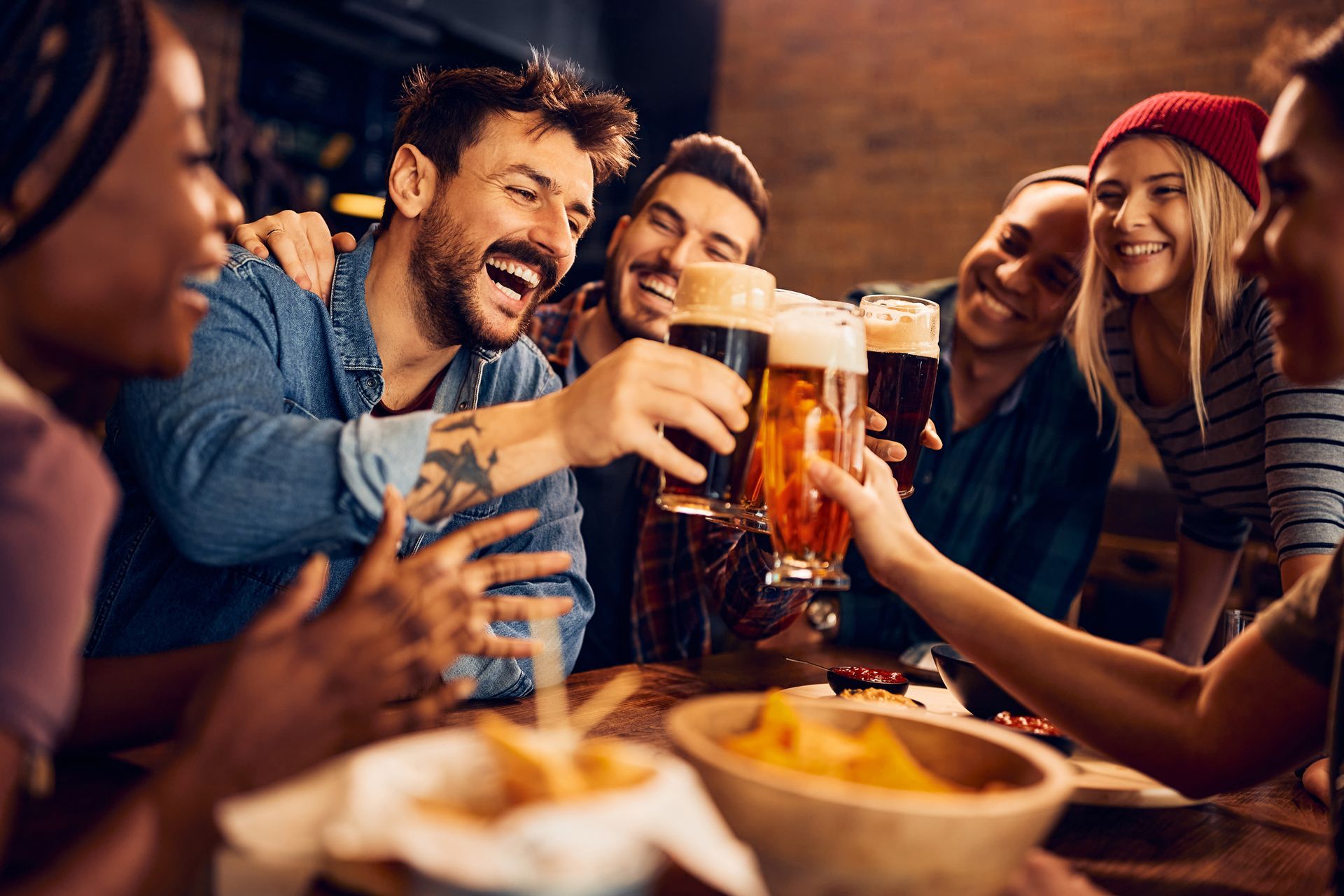 A group of people are toasting with beer in a bar.