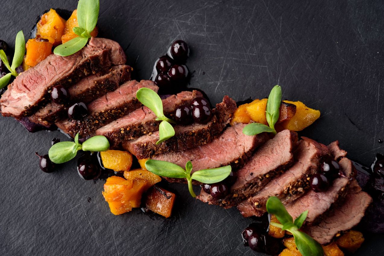 A close up of a plate of food with meat and vegetables on a table.