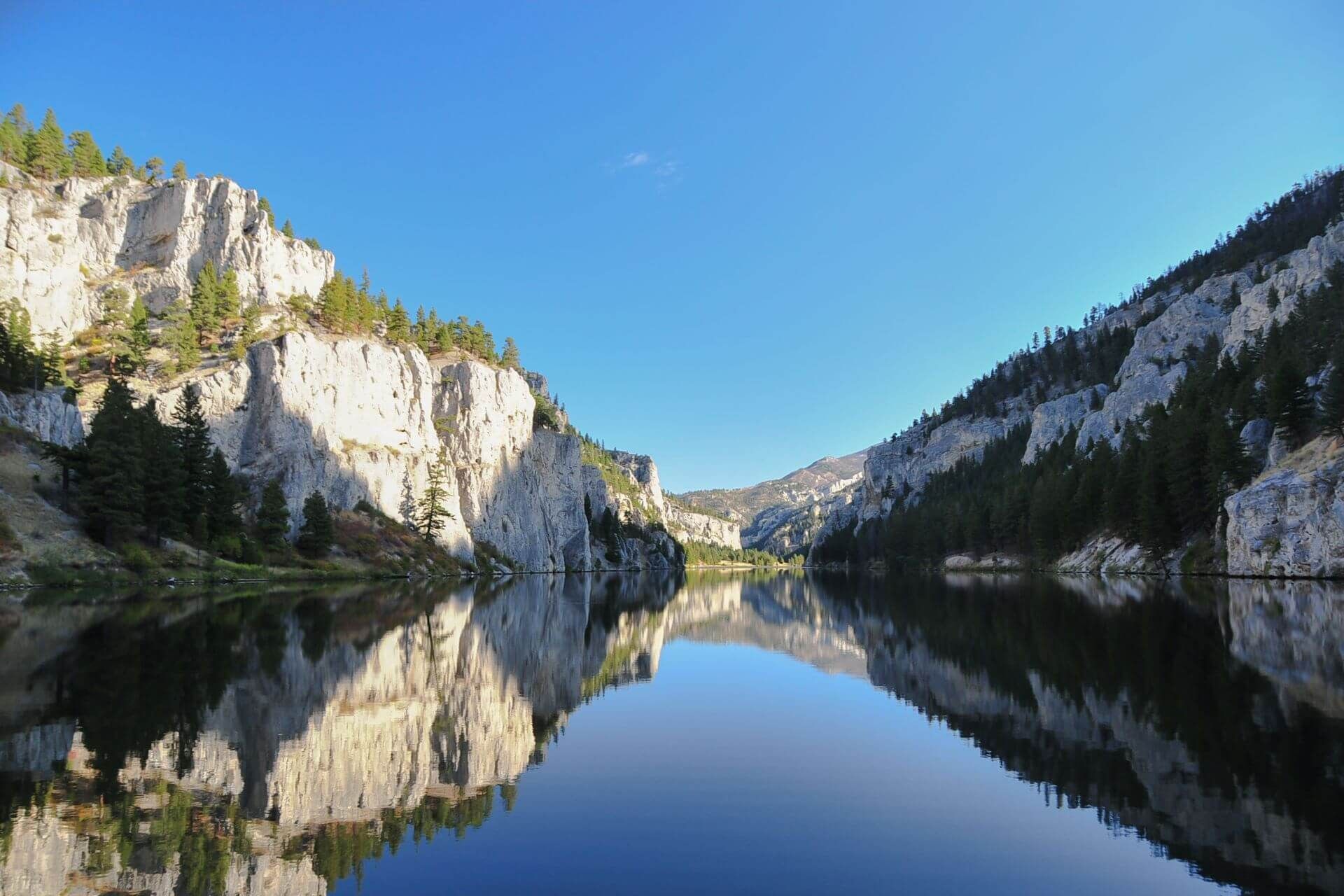 A lake surrounded by mountains and trees on a sunny day