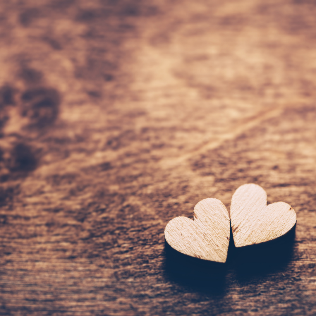 Two wooden hearts are sitting on a wooden table.