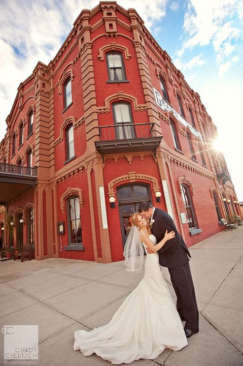 A bride and groom kissing in front of a red building