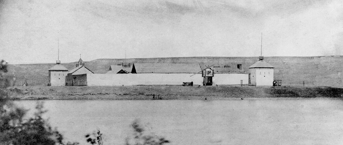 A black and white photo of a large building next to a body of water.