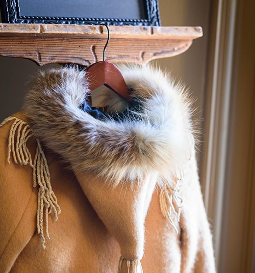 A fur coat with a hood is hanging on a shelf