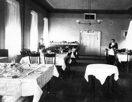 A black and white photo of a restaurant with tables and chairs