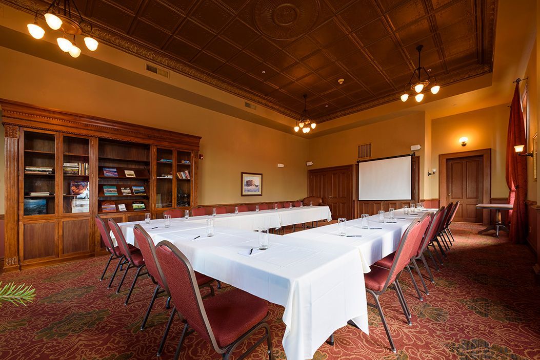 A large room with tables and chairs and a projector screen.