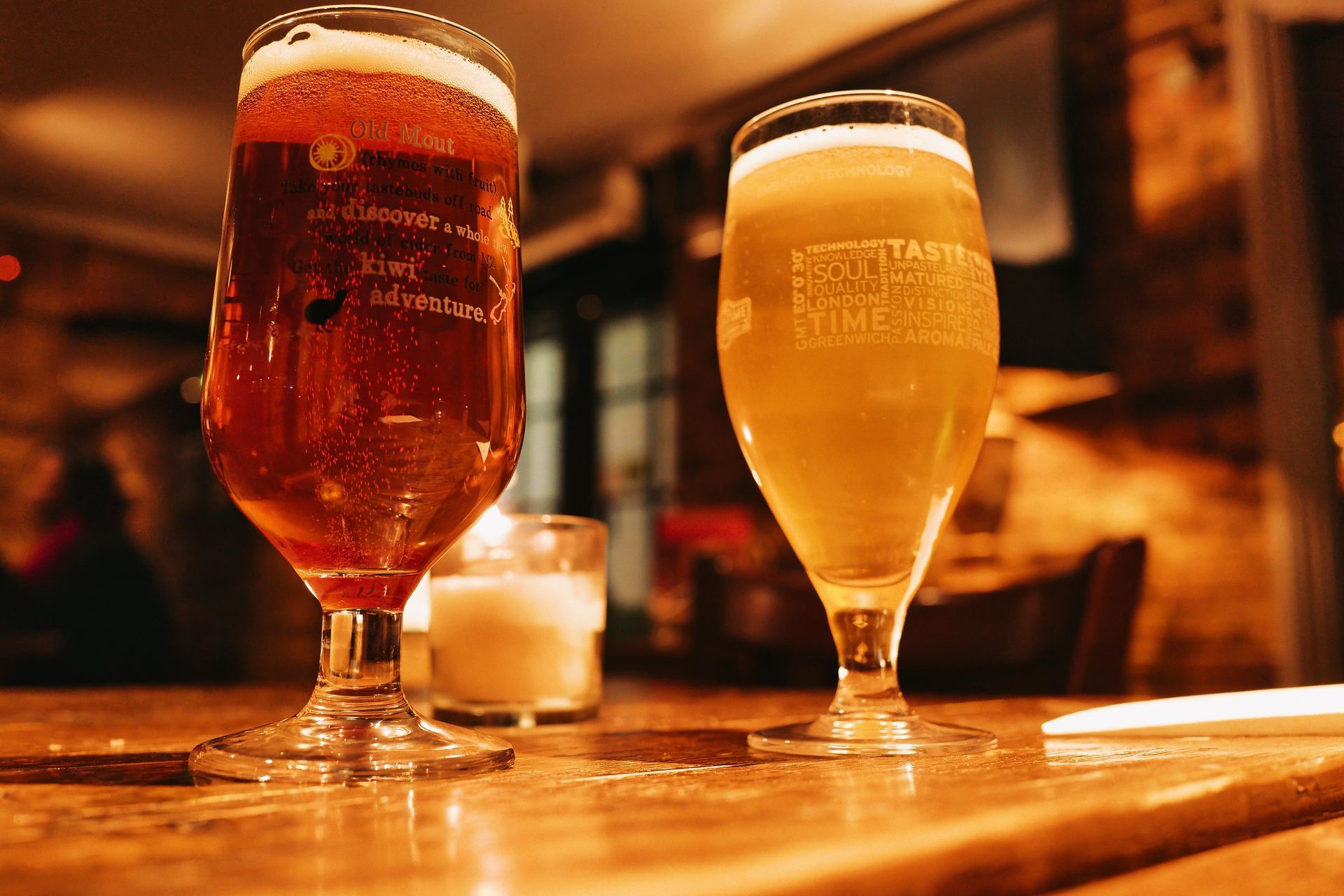 Two glasses of beer are sitting on a wooden table.