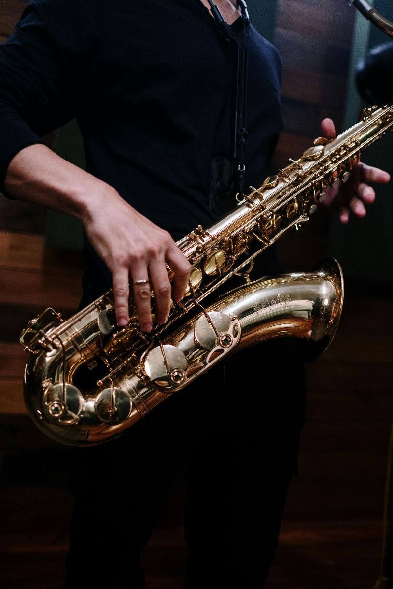 A man is playing a saxophone in a dark room.