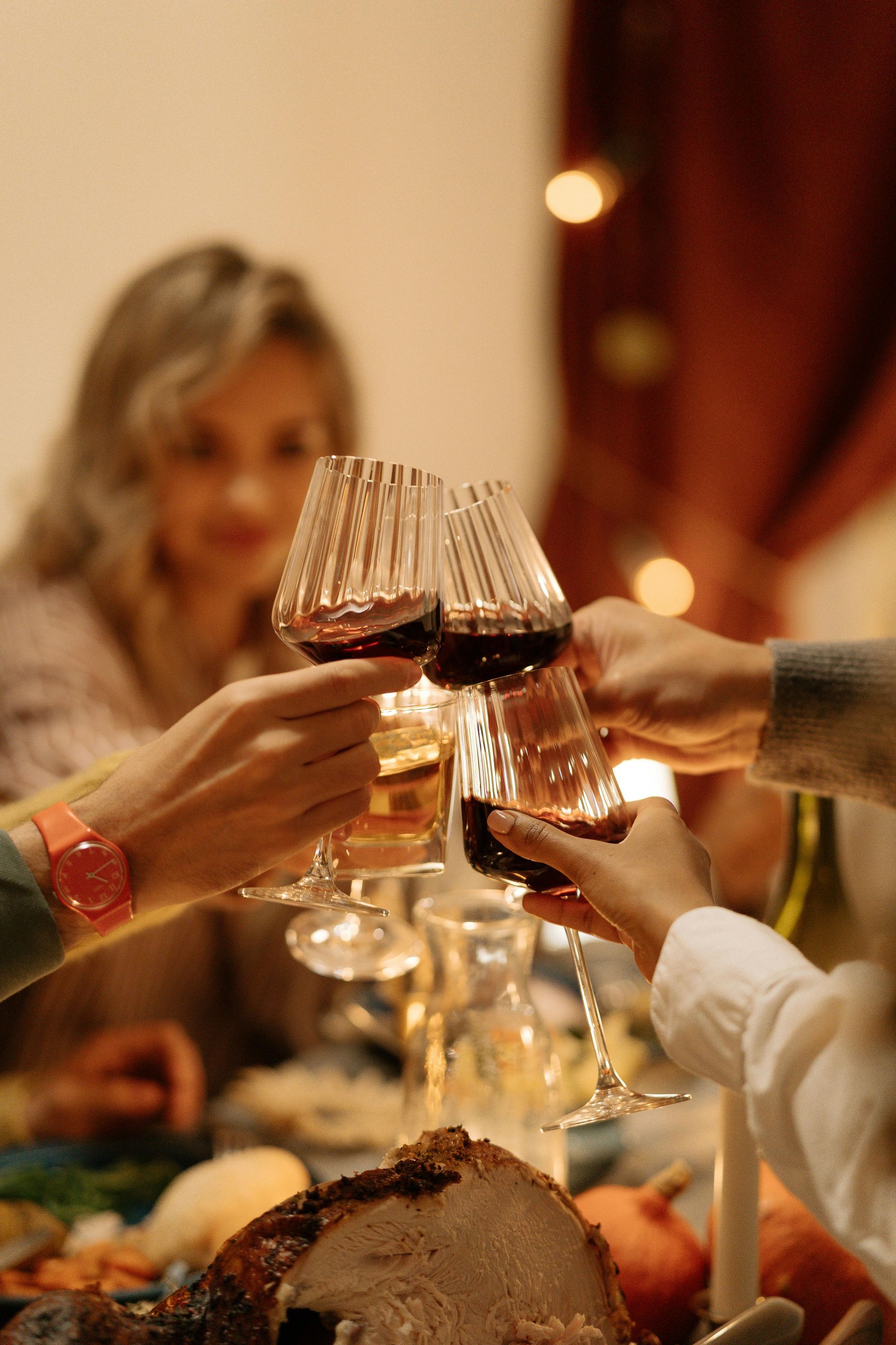 A group of people are toasting with wine glasses at a dinner table.