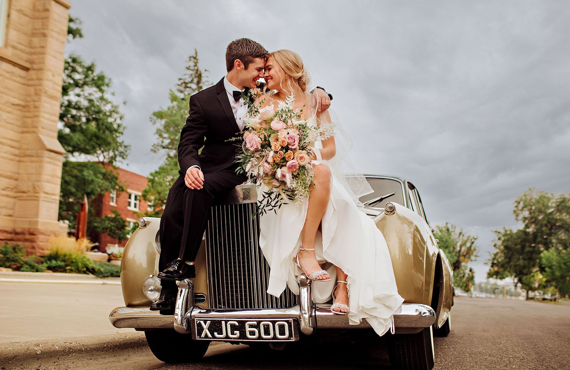 A bride and groom are kissing in a vintage car.
