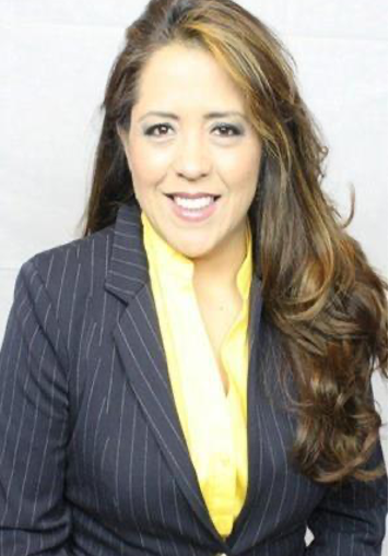 Woman in navy pinstripe blazer and yellow blouse smiles, looking at camera.