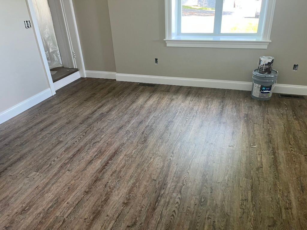 Woman in straw hat smiles, holding wine glass near a lake.