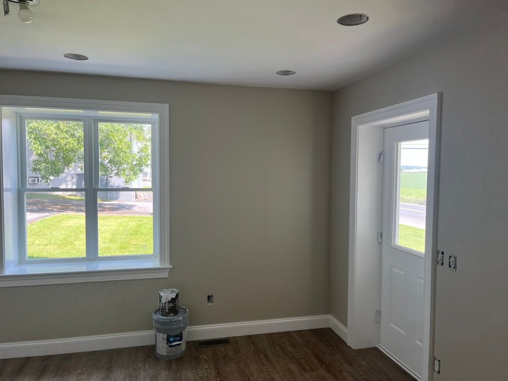 Woman in straw hat smiles, holding wine glass near a lake.