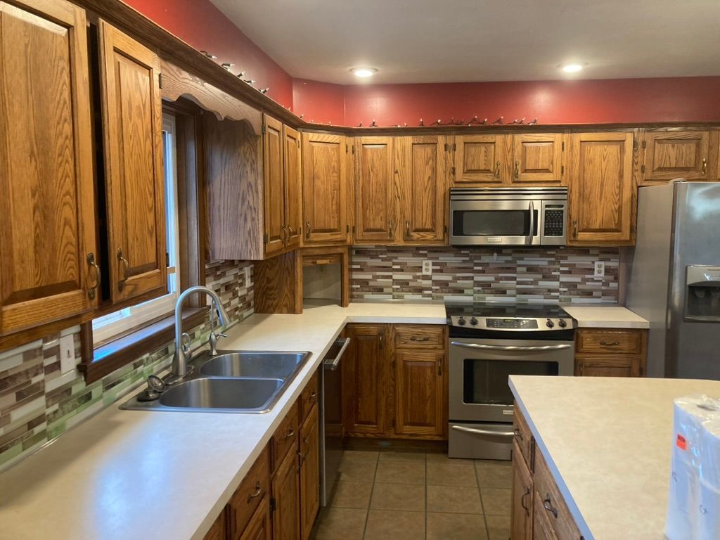 Woman in straw hat smiles, holding wine glass near a lake.