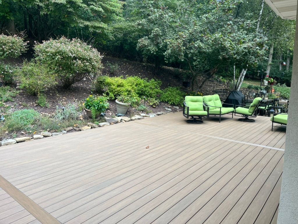 Woman in straw hat smiles, holding wine glass near a lake.