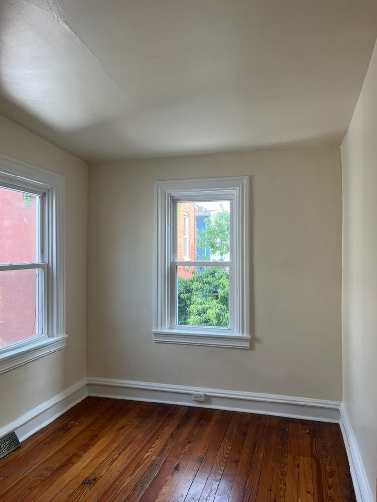 Woman in straw hat smiles, holding wine glass near a lake.