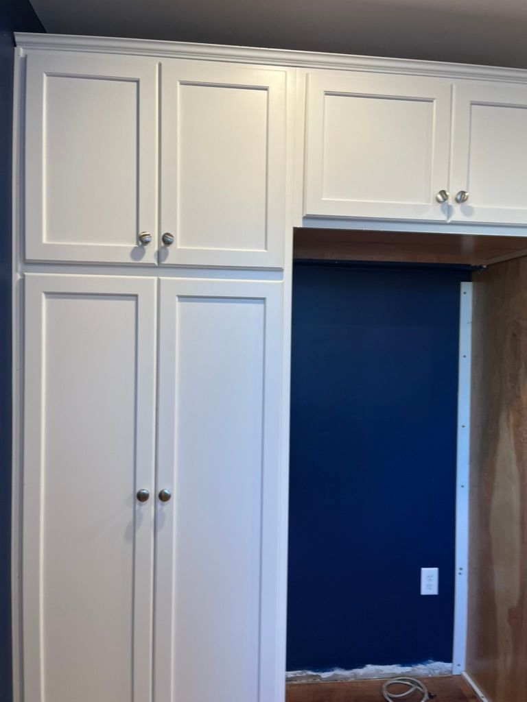 Woman in straw hat smiles, holding wine glass near a lake.