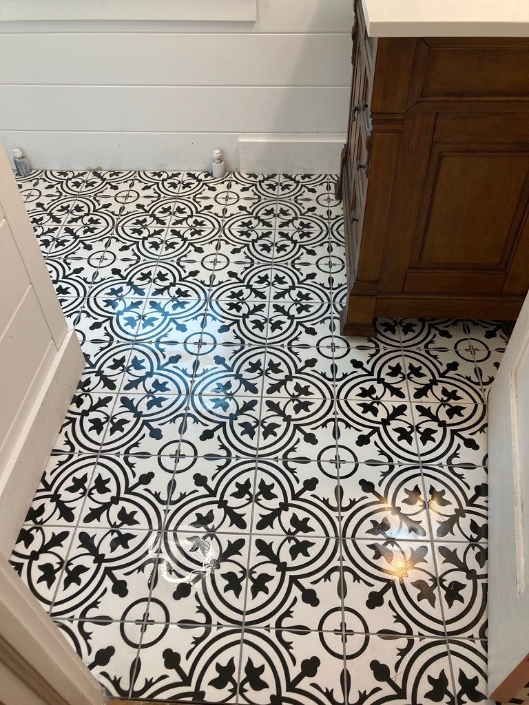 Woman in straw hat smiles, holding wine glass near a lake.