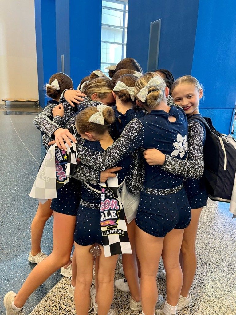 Cheerleading team huddling closely together, wearing matching uniforms.