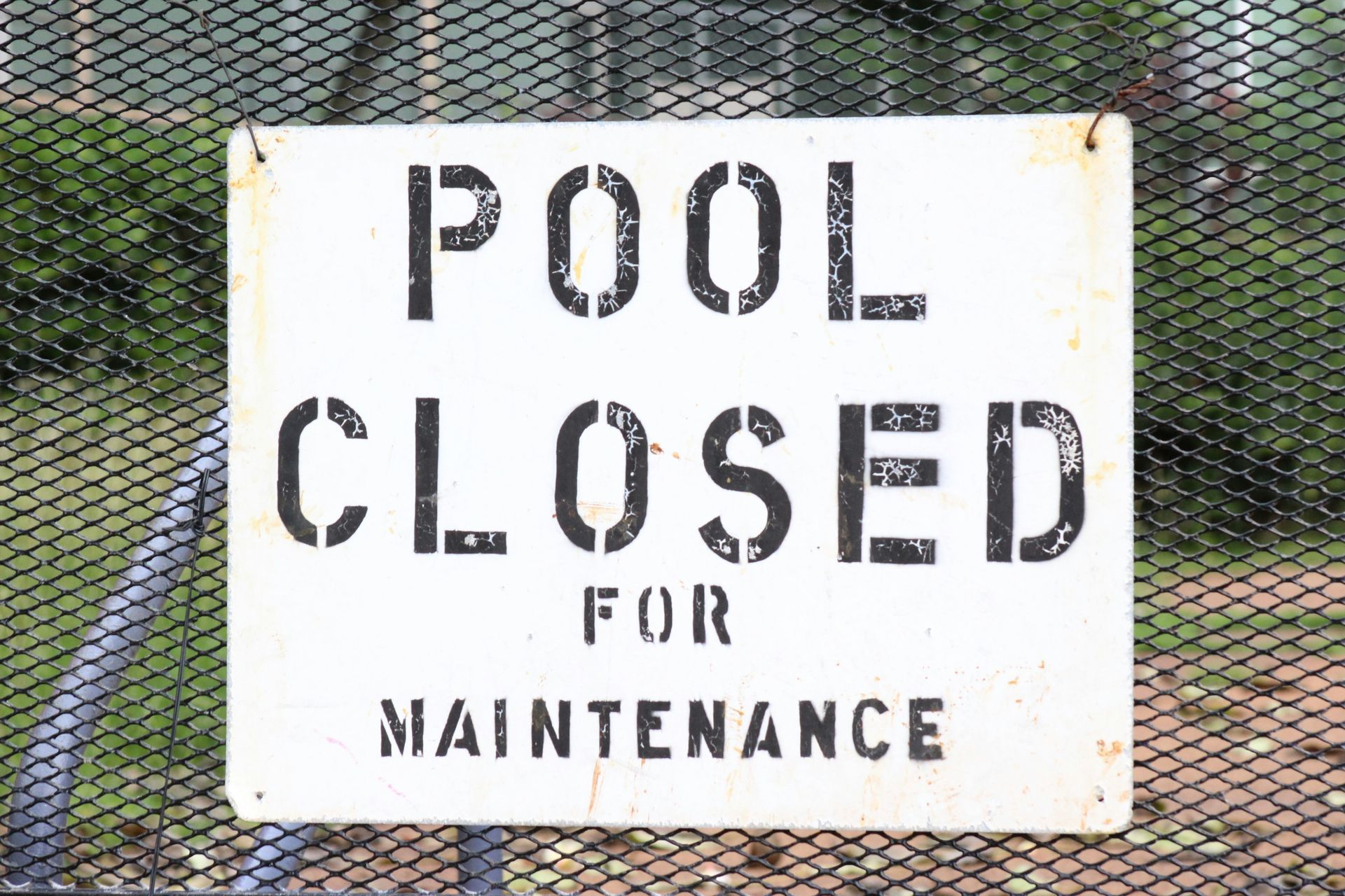 metal pool closed sign hanging on a pool fence. 