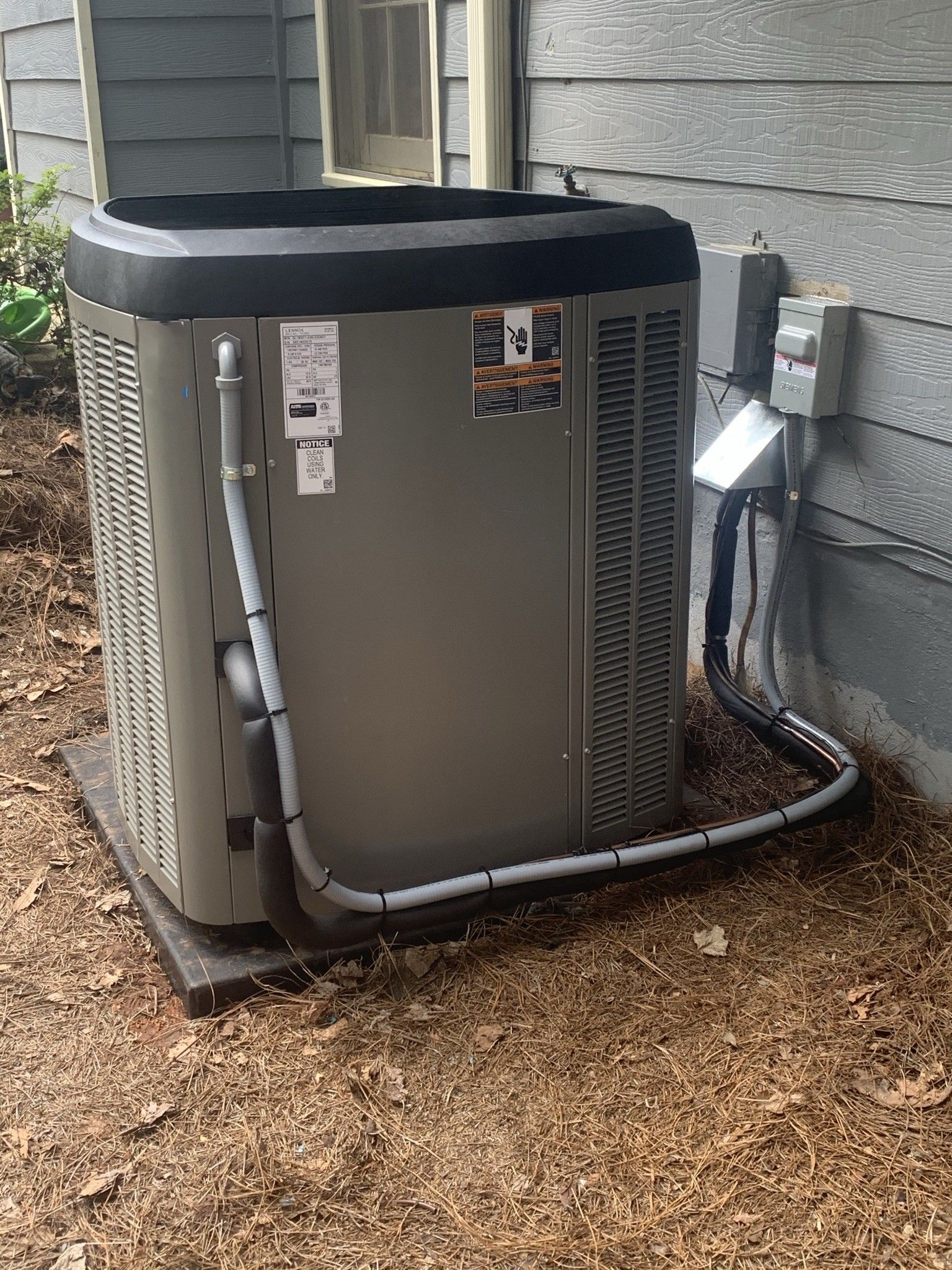 Inspector in yellow hard hat and vest examines a floor vent in a room with a window.