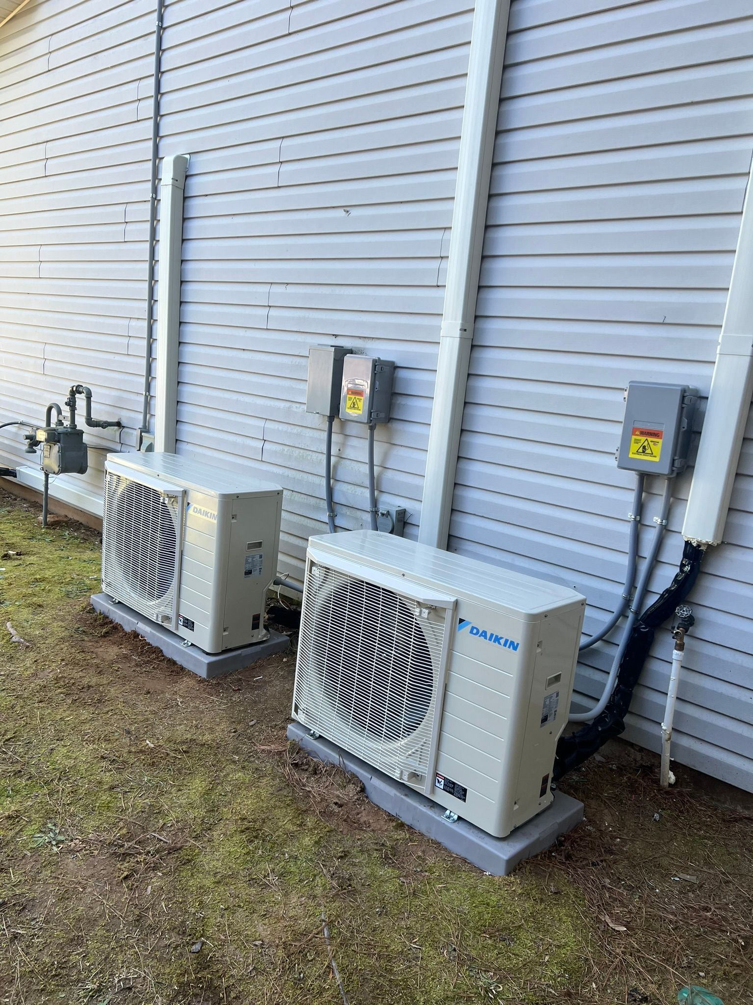 HVAC technician working on an outdoor unit. Orange tool belt, tools, brown cap, outside near a wooden wall.