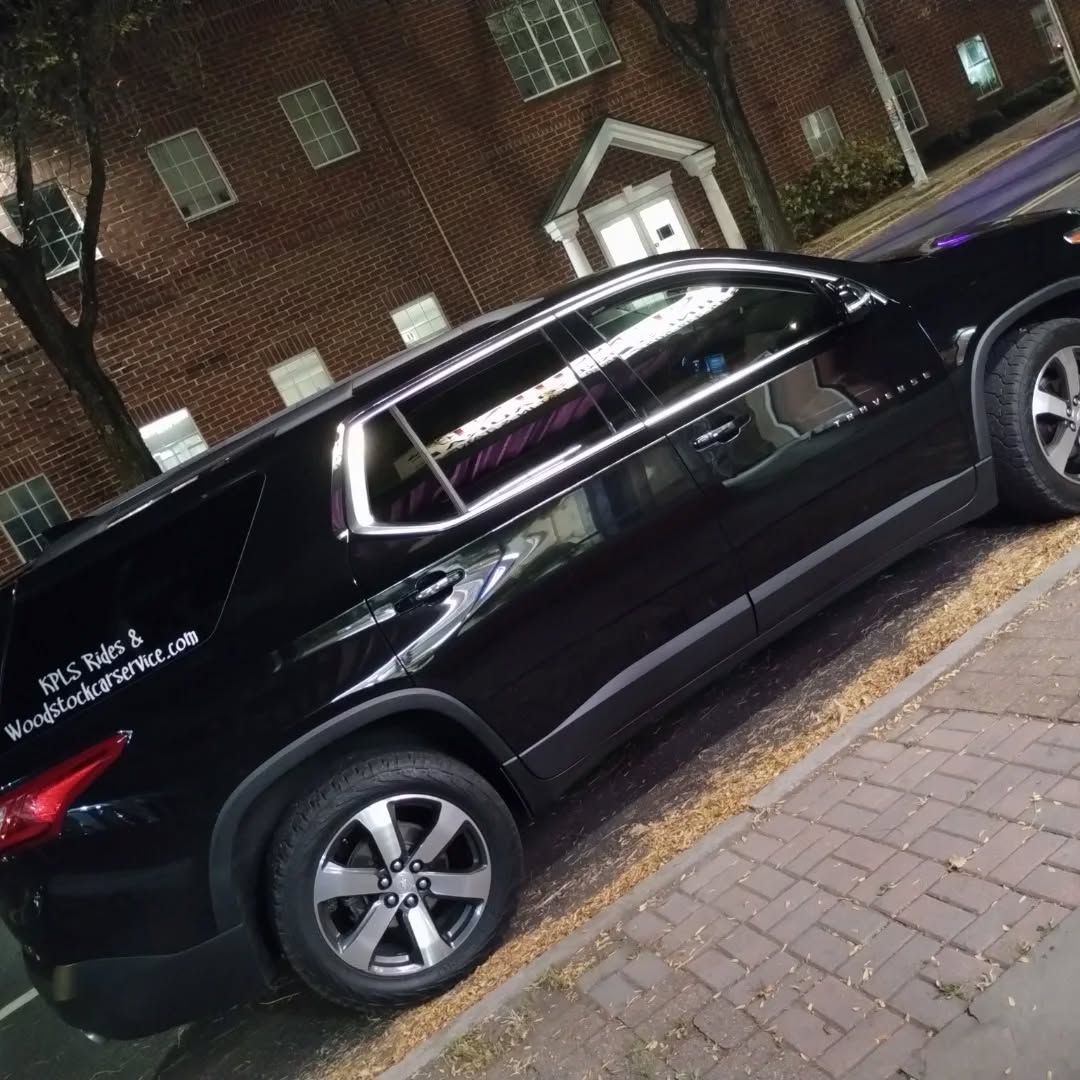 A black suv is parked in front of a brick building
