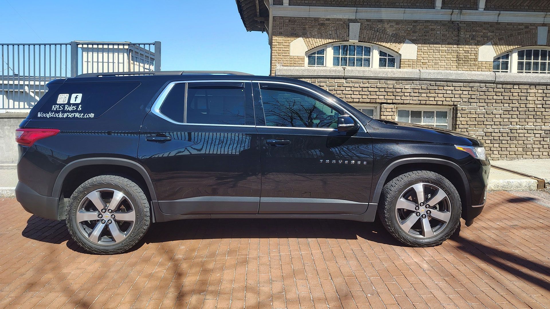 A black suv is parked in front of a stone building.