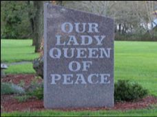 A large stone with the words `` our lady queen of peace '' written on it.