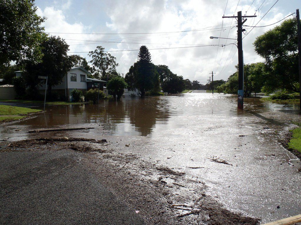 A flooded street with a telephone pole in the foreground
