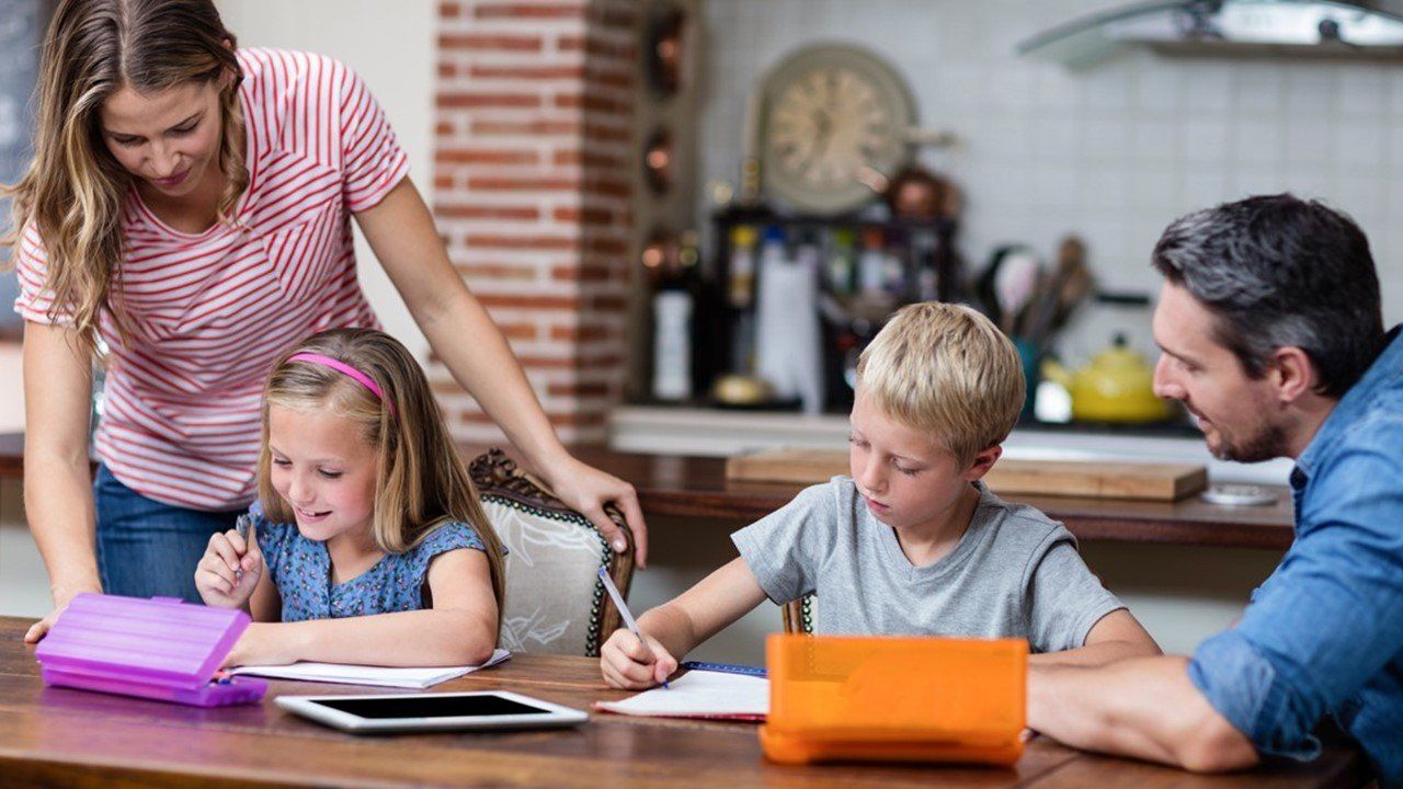 A family is sitting at a table doing their homework.