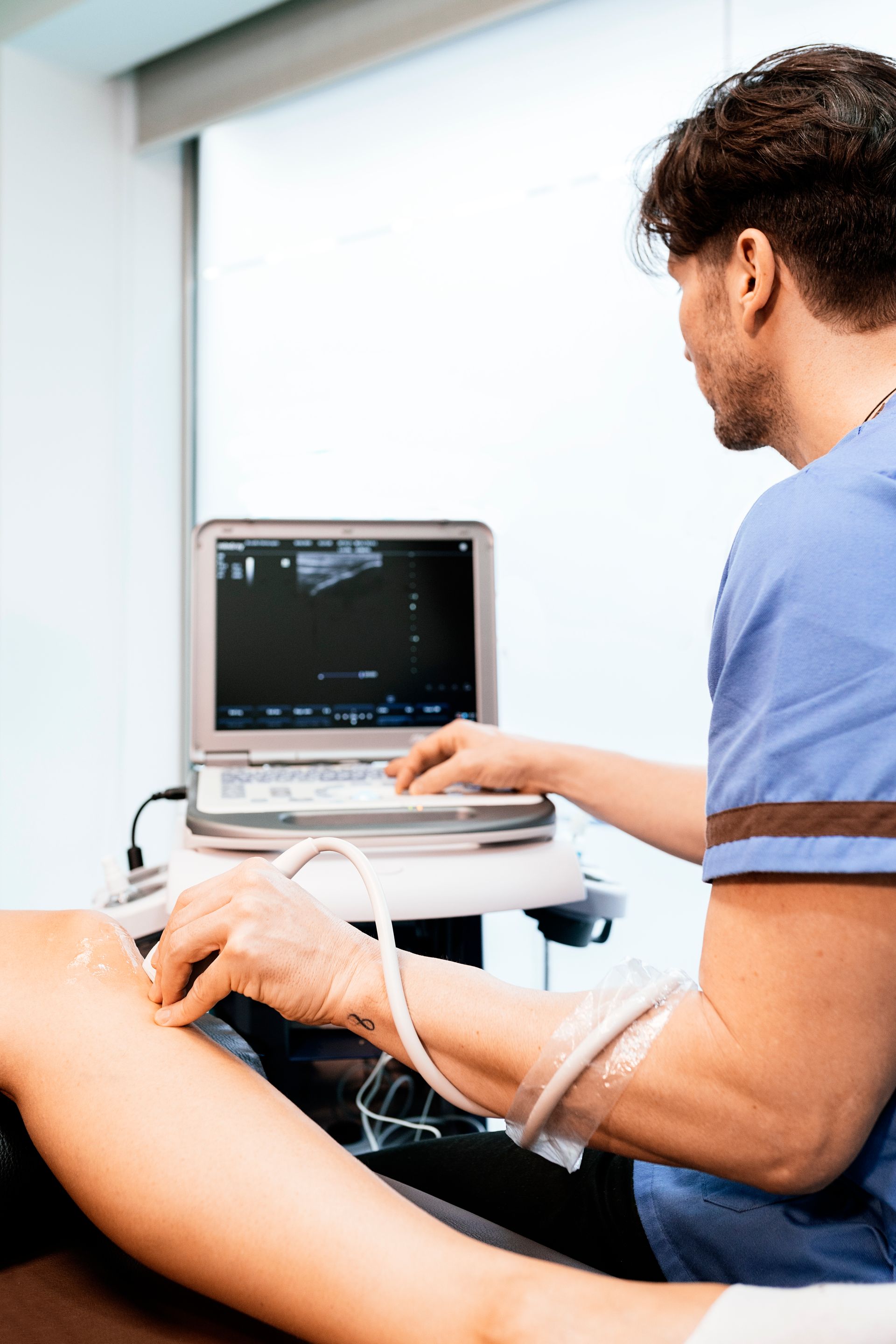 a man is using an ultrasound machine on a woman 's leg .