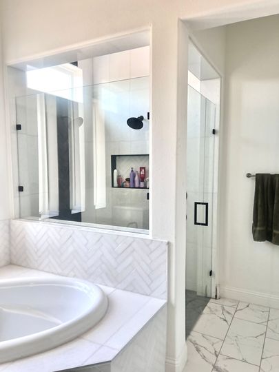 Modern bathroom with tan tile walls, a toilet, a glass-enclosed shower, a white vessel sink, and a heated towel rack.
