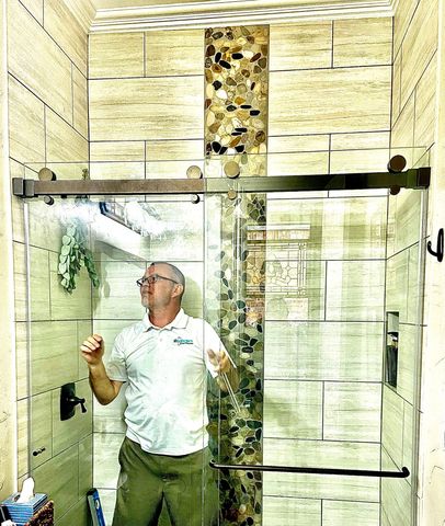 A person wearing gloves carefully positions a textured glass panel on a blue padded surface.