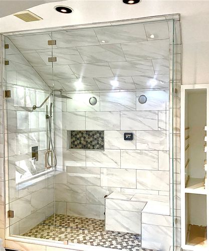 A neutral-toned bathroom with a glass-enclosed shower, a white vanity with a chrome faucet, and a toilet.