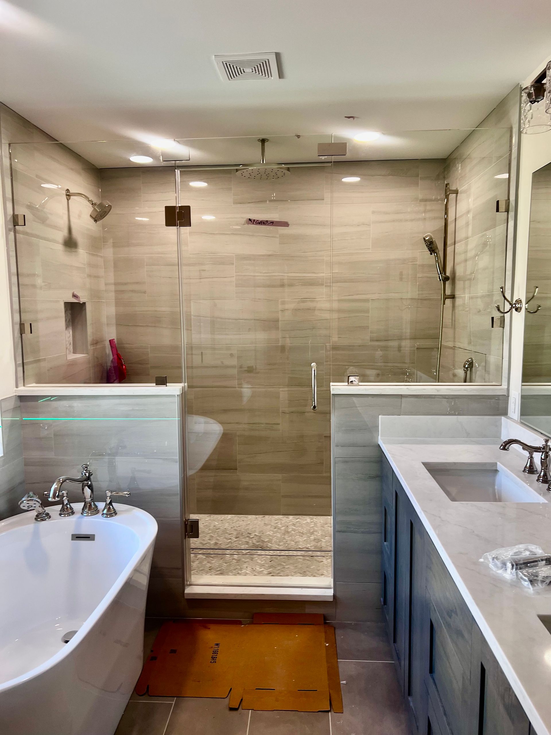 A modern bathroom featuring a white vanity with a chrome faucet and a glass-enclosed shower with a handheld showerhead.