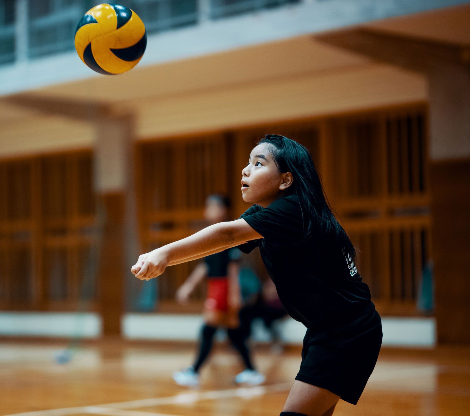 A young girl is playing volleyball in a gym.