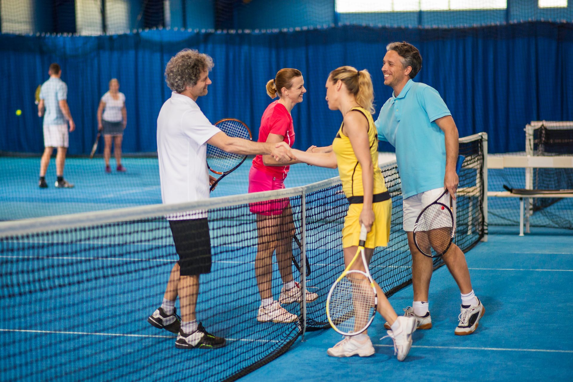 A group of people are shaking hands on a tennis court.