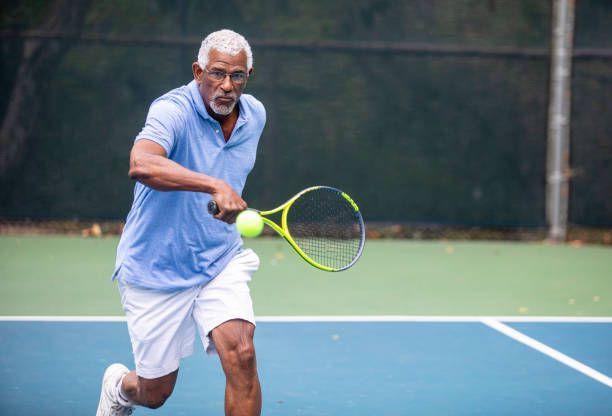 A man is playing a game of paddle tennis on a court.