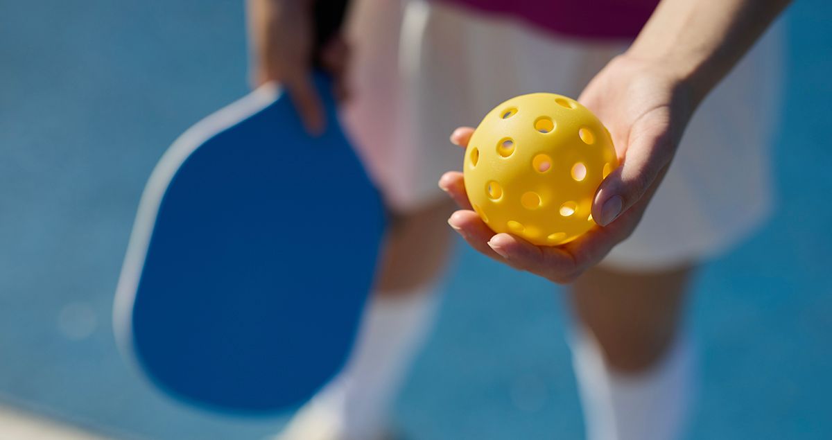 A woman is serving a tennis ball on a tennis court.