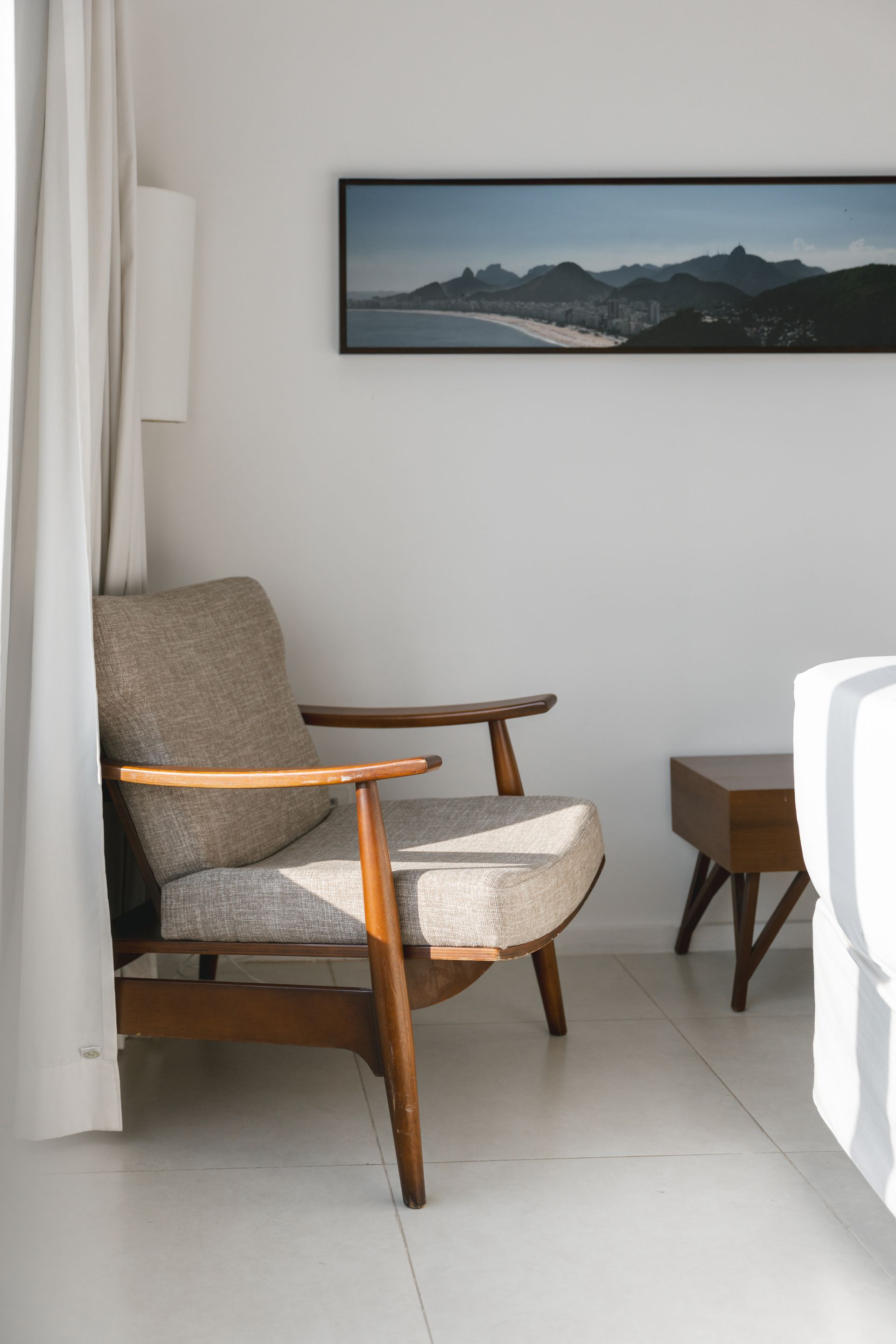 Uma poltrona moderna de meados do século em uma sala minimalista com uma foto de paisagem e mesa lateral.
