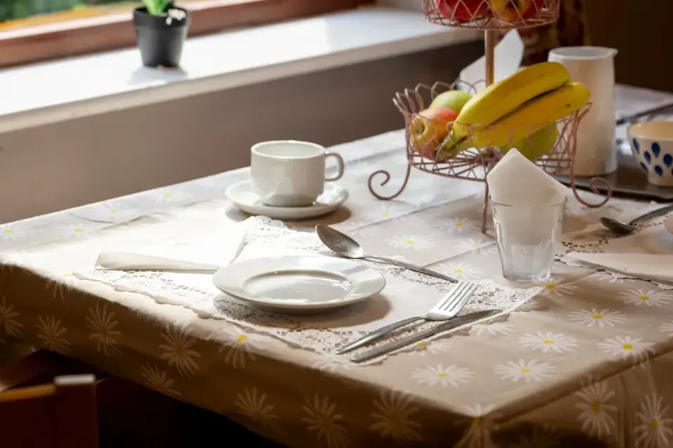 Oaklands Residential Care Home, Methley, Leeds | A table with plates , utensils , and a basket of bananas on it.