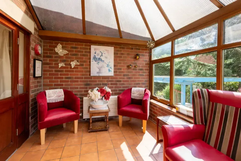 Oaklands Residential Care Home, Methley, Leeds | A living room with red chairs , a table and a painting on the wall.