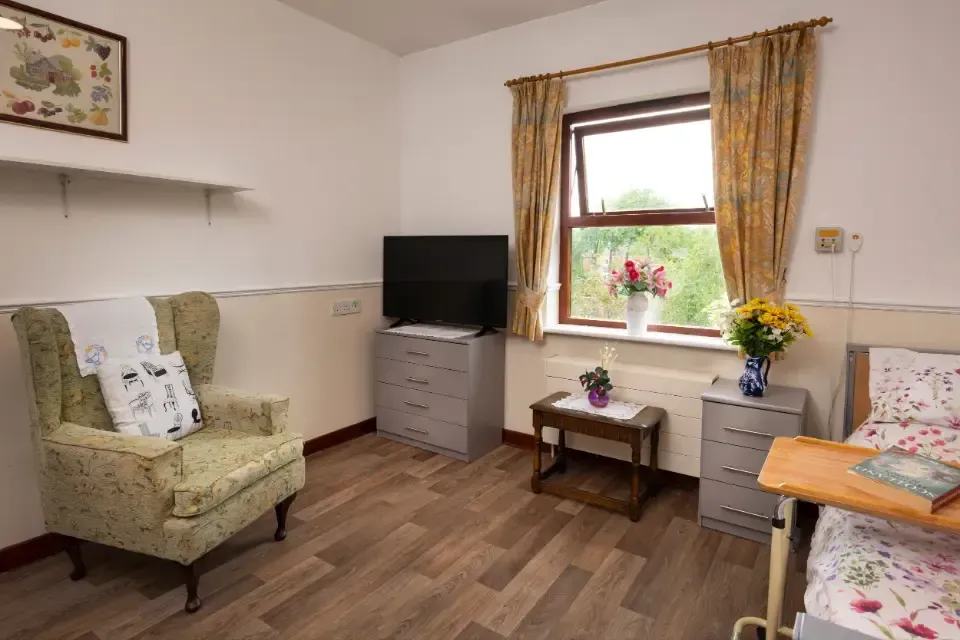 Oaklands Residential Care Home, Methley, Leeds | A bedroom with a bed , chair , television , nightstand and table.