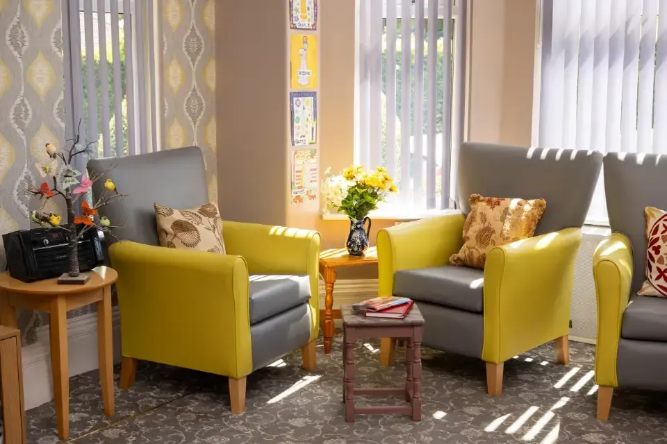 Oaklands Residential Care Home, Methley, Leeds | A living room with two yellow chairs and a table.