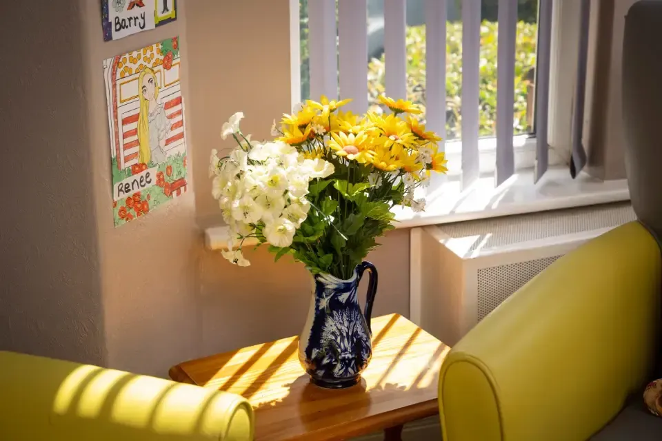 Oaklands Residential Care Home, Methley, Leeds | A vase of flowers is sitting on a table in front of a window.